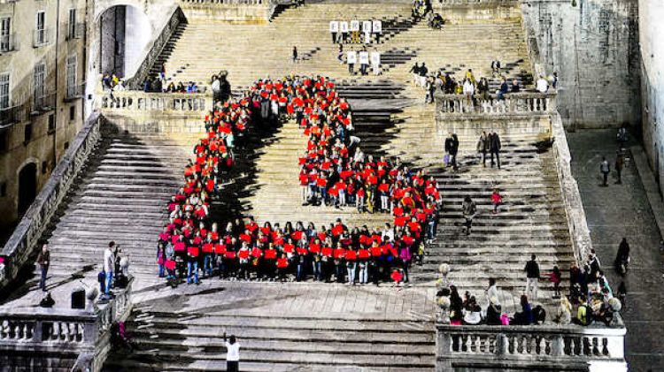 Moment de la construcció del 'cor humà gegant' que ha fet Càritas Girona a les escales de la catedral © ACN