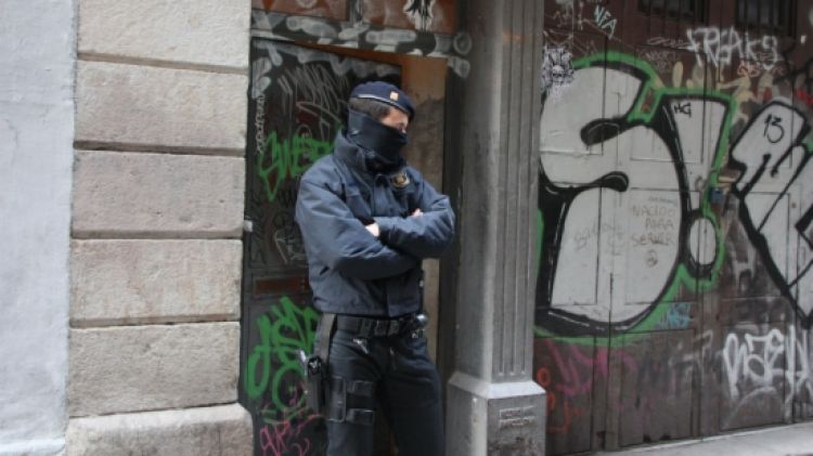 Un agent dels Mossos d'Esquadra custodia un portal en un dels registres al centre de Barcelona © ACN