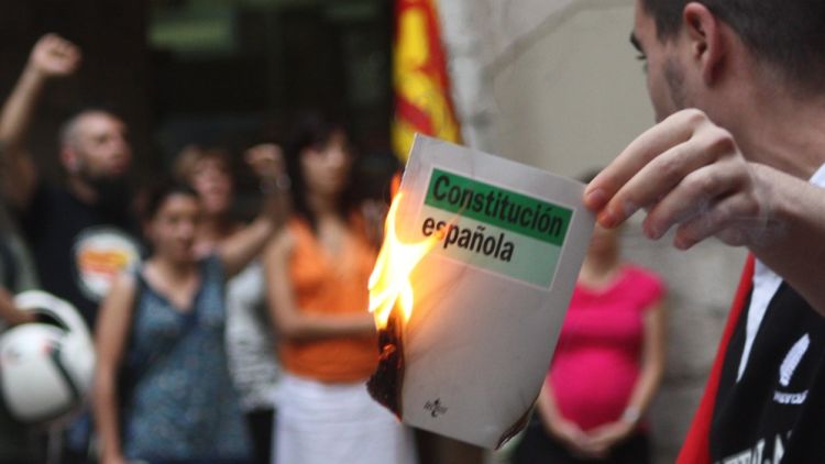 Un jove cremant un exemplar de la Constitució en un acte de la CUP a Girona © M. Estarriola